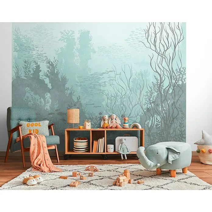 A.S. Création The Wall 3 Fototapete Unterwasser - B x H: 371 x 280 cm, Vlies - Kinderzimmer mit blauem Sessel, Holzregal und Elefantenhocker auf einem gemusterten Teppich vor einer Unterwasser-Tapete.