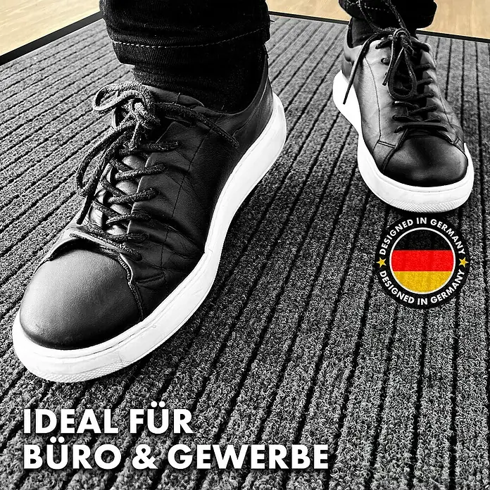 Fußmatte Dura - Grau, 120 x 66 cm, 100 % Polypropylen - Eine graue Fußmatte für Büro und Gewerbe mit schwarzen Schuhen und dem Aufdruck "Designed in Germany".