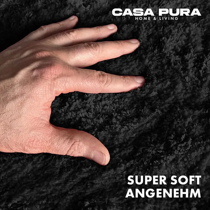 Floordirekt Badteppich Sky - 60 x 50 cm, Schwarz, 100% Polyester - Nahaufnahme eines Casa Pura Teppichs, der sich super weich und angenehm anfühlt. Die Hand berührt die weiche Oberfläche.