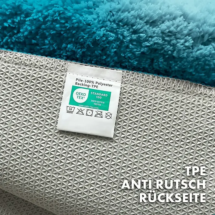 Floordirekt Badteppich Maris - 120 x 60 cm, Türkis, 100% Polyester - Nahaufnahme eines blauen Teppichs mit Etikett, das die Materialzusammensetzung und Pflegehinweise zeigt.