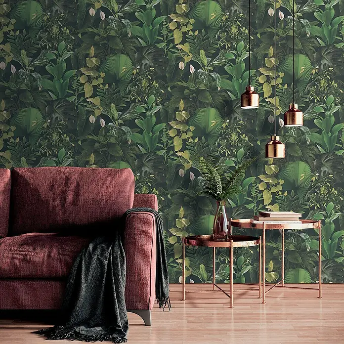 A.S. Création Pintwalls 2 Vliestapete Dchungel - Grün-Schwarz, Floral, 10,05 x 0,53 m - Das Bild zeigt ein gemütliches Wohnzimmer mit einem roten Sofa und einem Beistelltisch. Die Wand ist mit einer grünen Tapete mit Dschungelmotiven verziert.