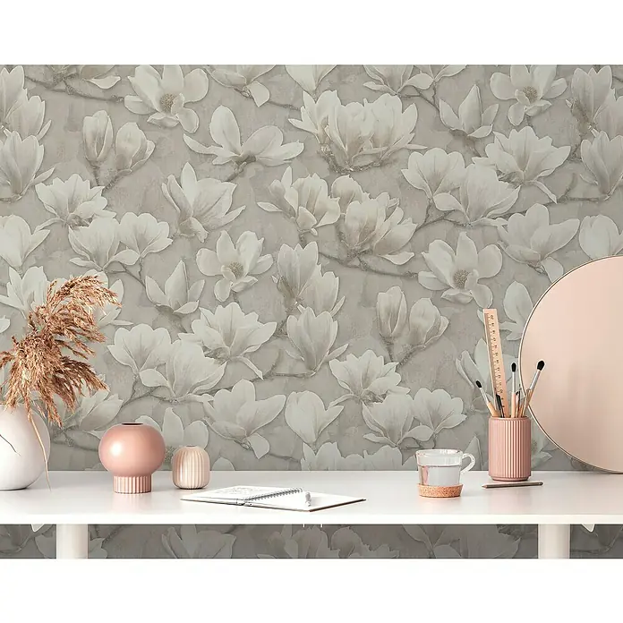A.S. Création Pintwalls 2 Vliestapete Magnolien - Beige-Creme-Weiß, Floral, 10,05 x 0,53 m - Nahaufnahme einer Tischplatte mit verschiedenen dekorativen Gegenständen wie Vasen, Stiften und einem Spiegel vor einer floralen Tapete.