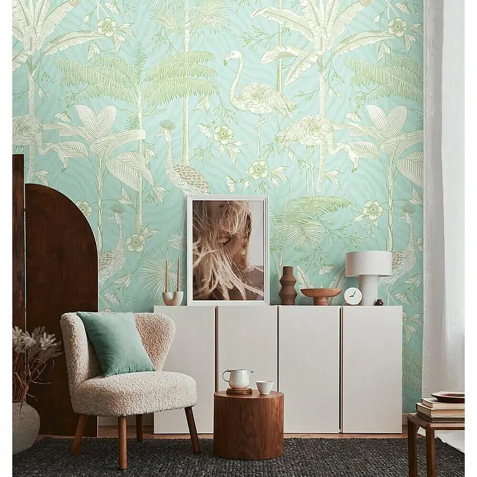 A.S. Création The Wall 2 Fototapete Flamingos - B x H: 159 x 280 cm, Vlies - Zimmer mit blauer Tapete, Sessel mit Kissen, Kommode und Beistelltisch. Die Tapete zeigt Palmen und Flamingos.