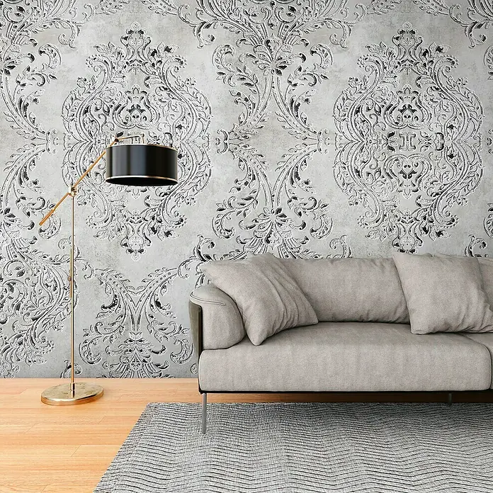 A.S. Création The Wall 3 Fototapete Relief - B x H: 159 x 280 cm, Vlies - Eine stilvolle Innenaufnahme mit einem modernen grauen Sofa, einer Stehlampe und einer gemusterten Tapete.
