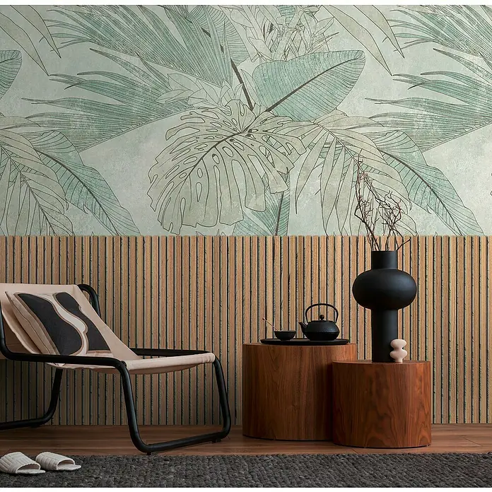 A.S. Création The Wall 3 Fototapete Holzpaneel mit Blätterausschnitt - B x H: 159 x 280 cm, Vlies - Einrichtungsidee mit einem schwarzen Teekessel und einer minimalistischen Vase auf Holzhockern vor einer Wand mit Pflanzenmuster.