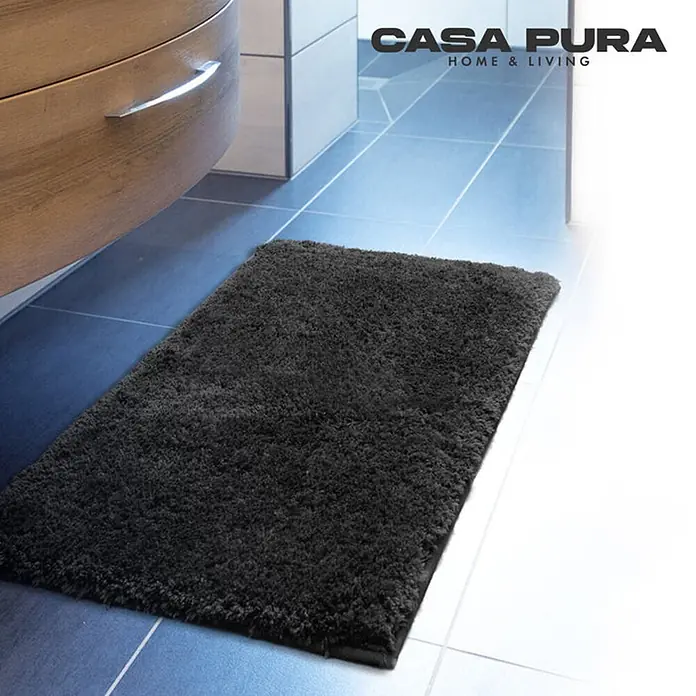 Floordirekt Badteppich Sky - 60 x 50 cm, Schwarz, 100% Polyester - Bild eines dunkelgrauen Casa Pura Badteppichs, der auf einem Badezimmerboden liegt. Der Teppich hat eine dichte, flauschige Textur.
