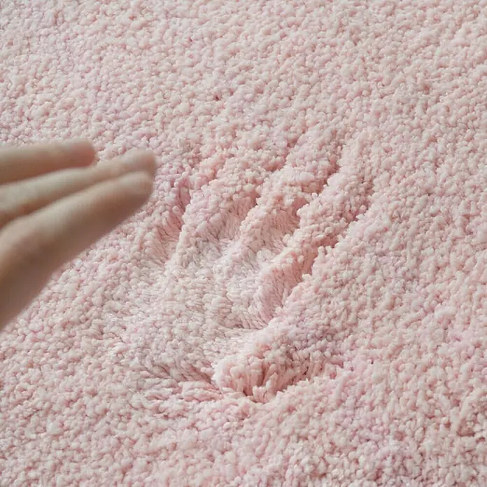 Floordirekt Badteppich Sky - 95 x 95 cm, Rosa, 100% Polyester - Nahaufnahme eines rosa Teppichs mit einem Handabdruck, der seine weiche Textur hervorhebt.