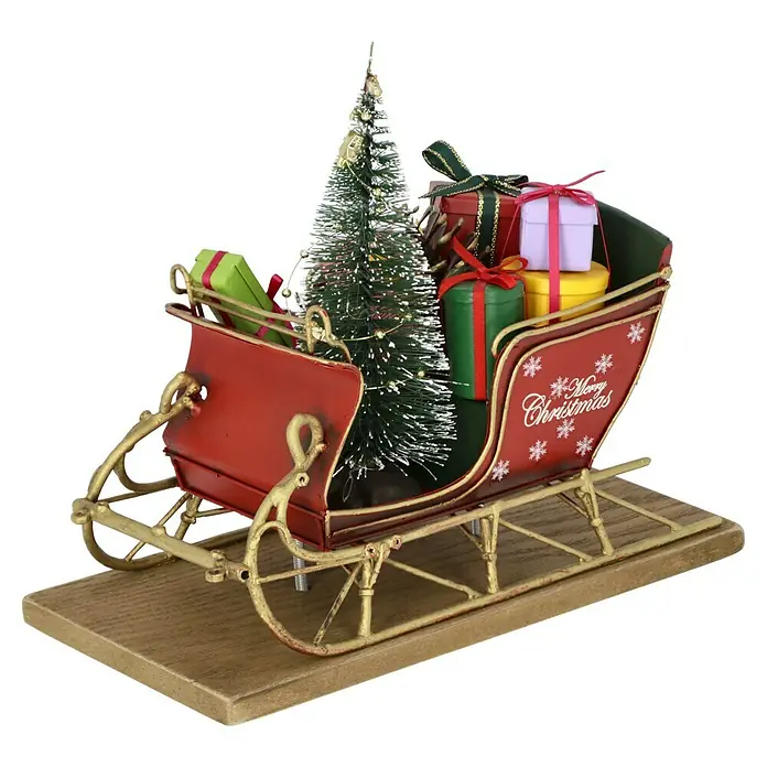 Dekofigur Weihnachtsschlitten - L x B x H: 22 x 10,5 x 18 cm, Metall - Nahaufnahme von einem festlichen roten Schlitten mit einem geschmückten Weihnachtsbaum und gestapelten Geschenken auf einem Holzsockel.