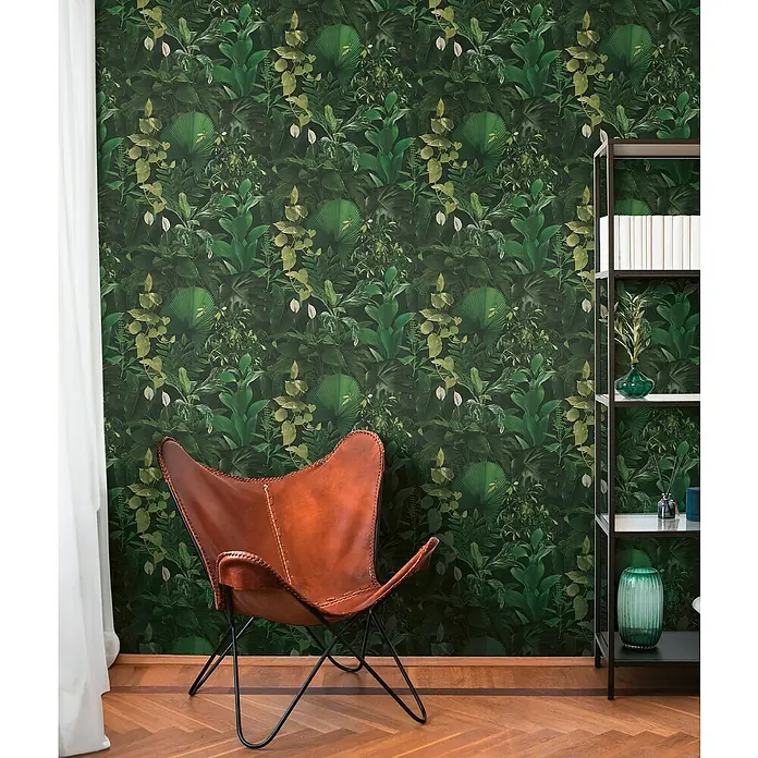 A.S. Création Pintwalls 2 Vliestapete Dchungel - Grün-Schwarz, Floral, 10,05 x 0,53 m - Brauner Ledersessel vor einer grünen Dschungeltapete und einem schwarzen Bücherregal.