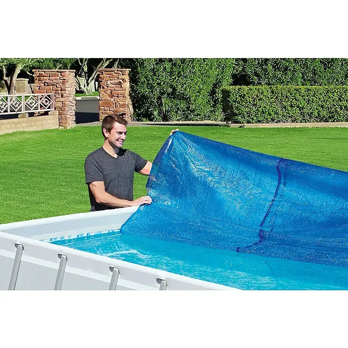 Bestway Solarabdeckplane - L x B: 180 x 380 cm, Material: Kunststoff - Der Mann legt eine blaue Poolabdeckung auf einen Pool, um ihn vor Schmutz zu schützen und die Wassertemperatur zu halten.