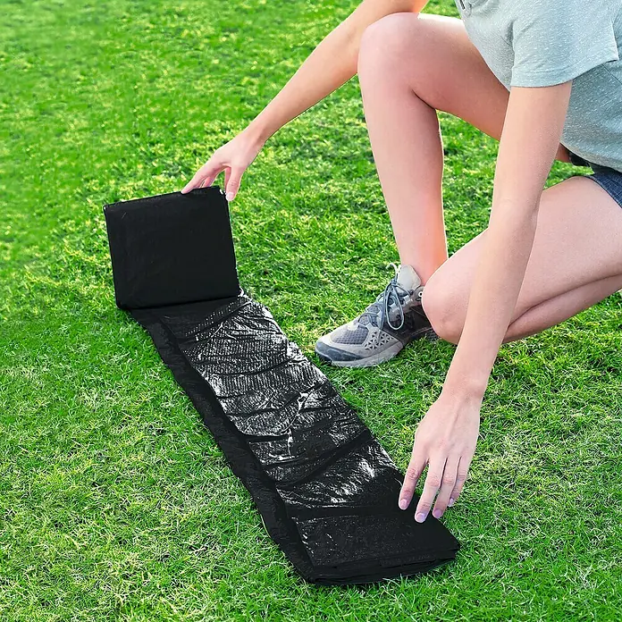 Bestway Pool-Abdeckplane - Durchmesser: 240 cm, Kunststoff - Frau, die eine schwarze Faltmatratze auf grünem Gras ausbreitet. Ideal für Outdoor-Aktivitäten.