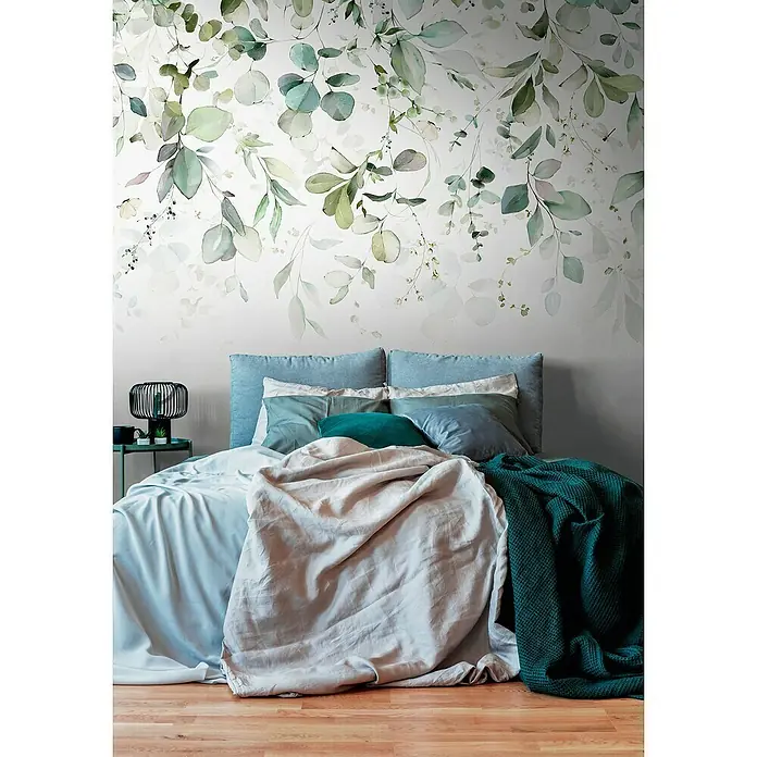 A.S. Création The Wall 3 Fototapete Blätter - B x H: 371 x 280 cm, Vlies - Schlafzimmer mit Bett, blauen Kissen und einer grünen Decke vor einer Wand mit Eukalyptus-Blätter-Muster für eine entspannende Atmosphäre.
