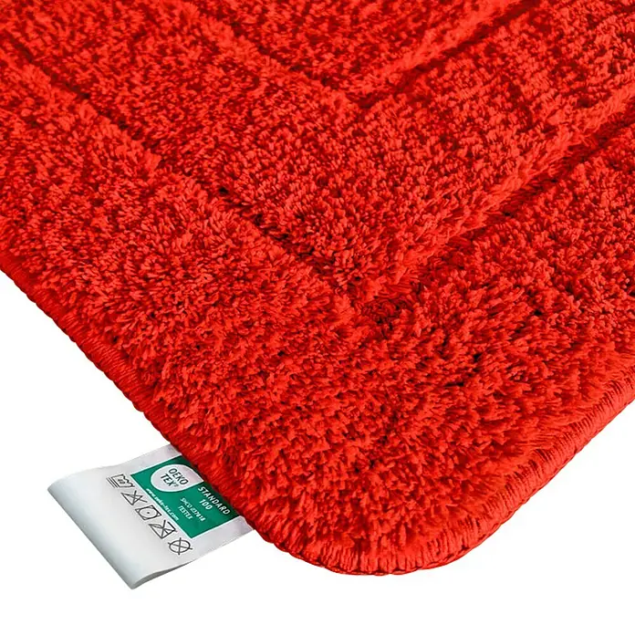 Floordirekt Badteppich Atlantis - 120 x 70 cm, Rot, 100% Polyester - Nahaufnahme eines roten Badteppichs mit Öko-Tex-Siegel, der für Qualität und Schadstofffreiheit steht. Der Teppich ist flauschig und weich.