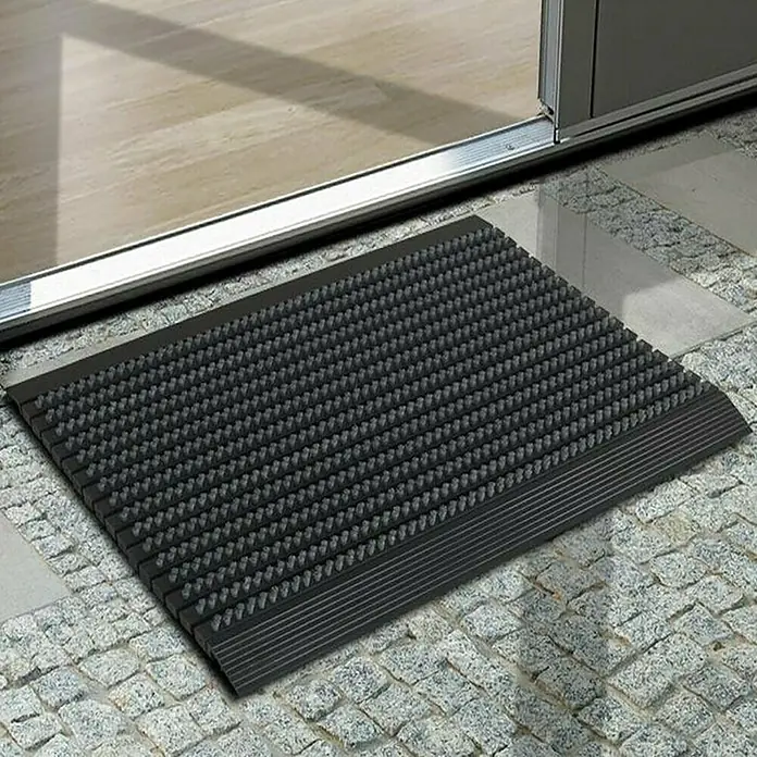 Fußmatte Power Brush - Grau, 60 x 40 cm, 100 % Nylon - Schwarze Fußmatte mit Noppen vor einer Tür.
