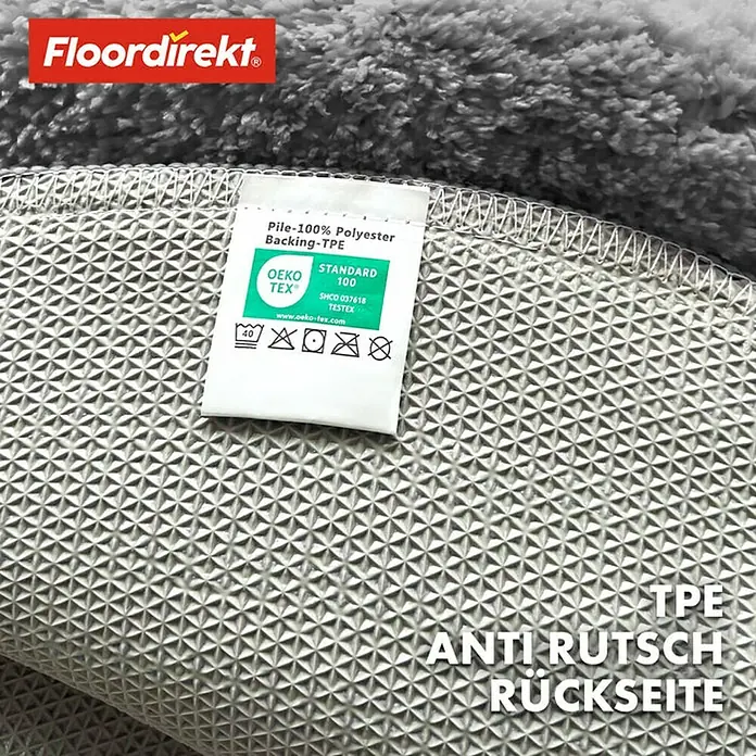 Floordirekt Badteppich Sky - 95 x 95 cm, Silbergrau, 100% Polyester - Detailaufnahme eines Floordirekt-Teppichs, der die TPE-Antirutsch-Rückseite und das OEKO-TEX-Label für Materialzusammensetzung zeigt.