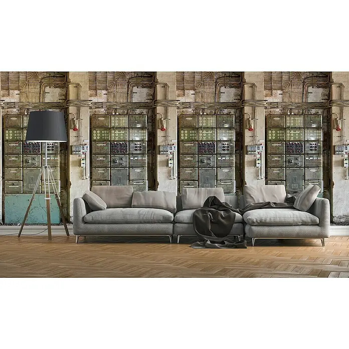 A.S. Création The Wall 2 Fototapete Fabrikhalle Sicherungskasten - B x H: 159 x 280 cm, Vlies - Elegante graue Couch mit Kissen und Decke vor einer Wand mit Schalttafeln und Rohren, beleuchtet durch eine Stehlampe.