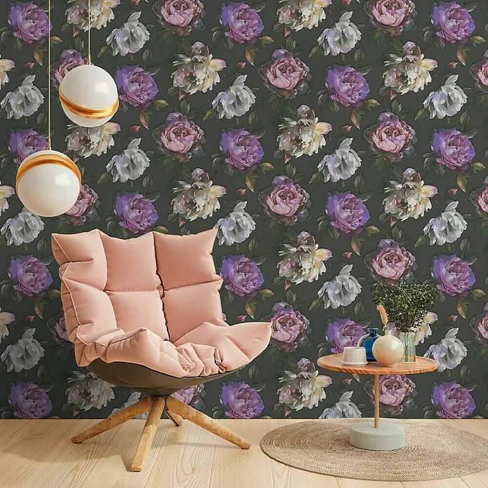 A.S. Création Pintwalls 2 Vliestapete Pfingstrosenblüten - Schwarz-Violett-Grün, Floral, 10,05 x 0,53 m - Wohnzimmer-Szene mit einem stilvollen, altrosa Sessel und einem Beistelltisch, dekoriert mit Blumen und Keramik, vor einer floralen Tapete.