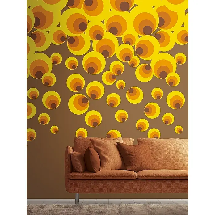 A.S. Création The Wall 2 Fototapete Kreise - B x H: 159 x 280 cm, Vlies - Gemütliches braunes Sofa mit Kissen vor einer Wand mit Retro-Kreismuster, das eine warme und einladende Atmosphäre schafft.