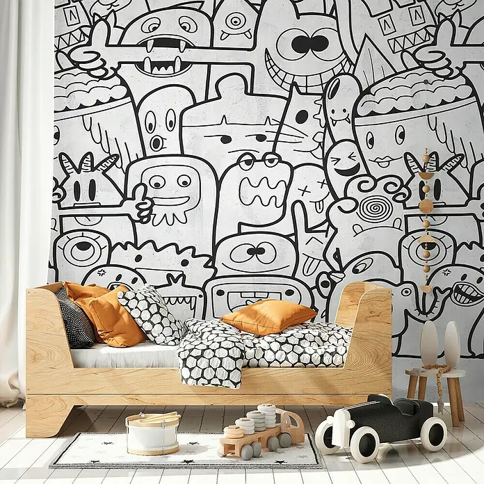 A.S. Création The Wall 3 Fototapete Comic - B x H: 159 x 280 cm, Vlies, Schwarz-Weiß - Kinderzimmer mit Holz-Tagesbett, bunten Kissen und Spielzeug vor einer lustigen Monster-Tapete für eine verspielte Atmosphäre.