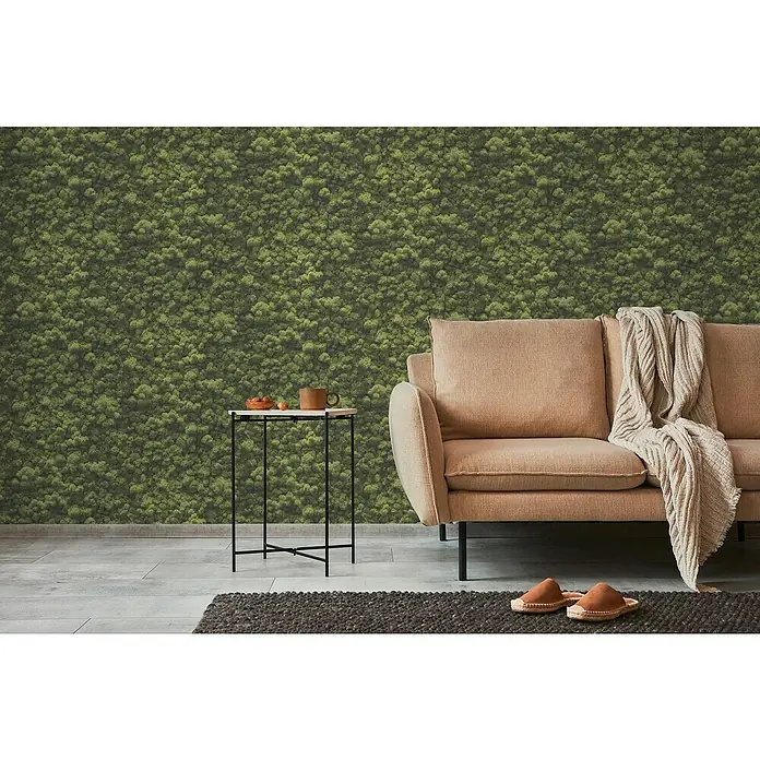 A.S. Création Pintwalls 2 Vliestapete Mooswand - Grün, Floral, 10,05 x 0,53 m - Gemütliches Wohnzimmer mit beigem Sofa, kleinem Beistelltisch und einem grünen Mooswandpaneel für eine natürliche Atmosphäre.