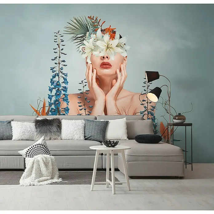 A.S. Création The Wall 3 Fototapete Frau - B x H: 371 x 280 cm, Vlies - Stilvolles Wohnzimmer mit grauem Sofa, Zierkissen und einem auffälligen Wandbild, das eine Frau mit Blumen im Gesicht zeigt. Die Lampe sorgt für Ambiente.