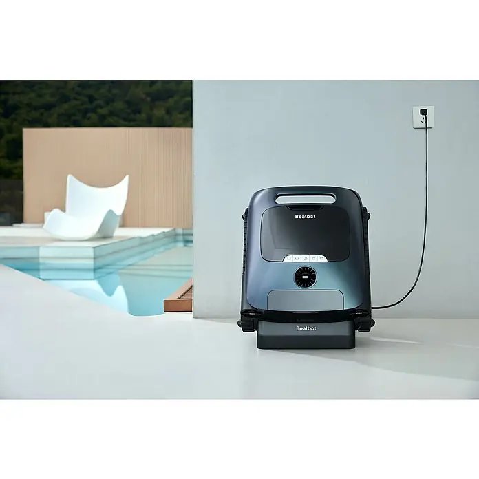 Beatbot Poolroboter AquaSense 2 Pro - Akkubetrieben, Passend für: Pools bis 360 m² Grundfläche, Filterleistung: 20.800 l/h - Der Beatbot Poolroboter steht auf einer weißen Oberfläche neben einem Pool und ist an eine Steckdose angeschlossen.