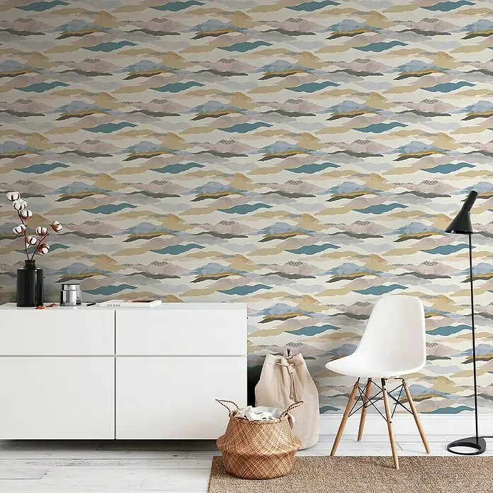 A.S. Création Pintwalls 2 Vliestapete Wolken-Wellen - Blau-Rosa-Beige, Grafisch, 10,05 x 0,53 m - Gemütliches Interieur mit gemusterten Wandtapeten in Form von stilisierten Wolken, einem weißen Sideboard, einem Korb und einer weißen Stuhl.