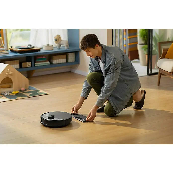 Roborock Saugwischroboter Q10 VF Black - Saugkraft: 10.000 Pa, Akkulaufzeit: 150 min, Fassungsvermögen Roboter: 500 ml, Schwarz - Ein Mann befestigt das Zubehör an einem schwarzen Roboterstaubsauger auf einem Holzboden, um eine optimale Reinigungsleistung zu erzielen.