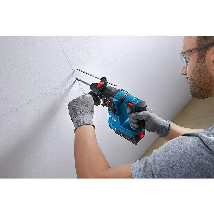Bosch Professional AMPShare 18V Akku-Bohrhammer GBH 18V-18 - 18 V, Ohne Akku, 1,5 J - Ein Handwerker bohrt mit einer Bosch Akku-Bohrmaschine ein Loch in eine Wand, präzise und kraftvoll für Bauprojekte.