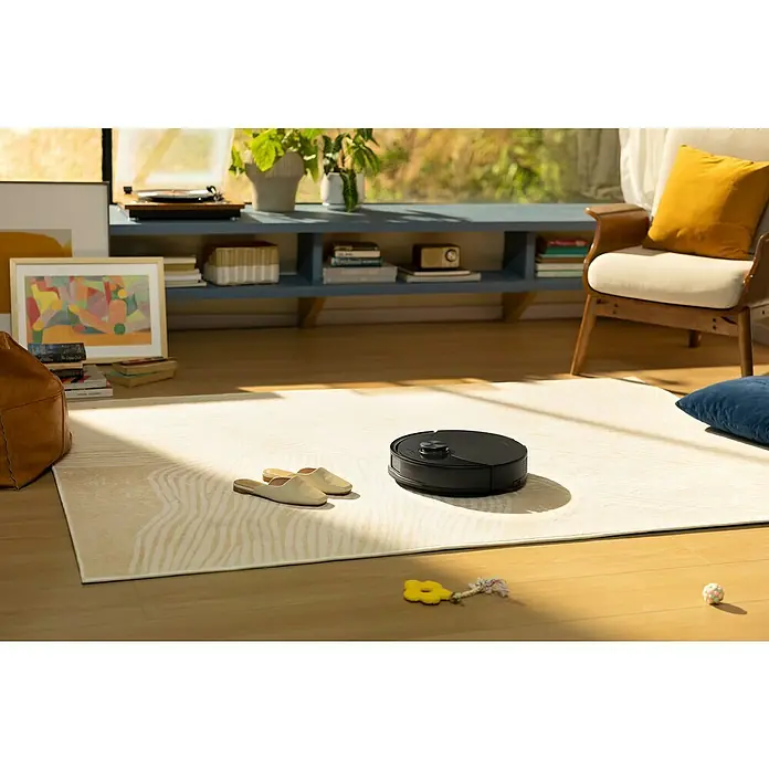 Roborock Saugwischroboter Q10 VF Black - Saugkraft: 10.000 Pa, Akkulaufzeit: 150 min, Fassungsvermögen Roboter: 500 ml, Schwarz - Ein Roboterstaubsauger reinigt einen hellen Teppich in einem gemütlichen Wohnzimmer. Das Gerät ist der Star der modernen Haushaltsführung.