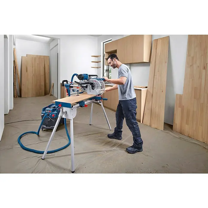 Bosch Professional Kapp- & Gehrungssäge GCM 340-305D - 1.800 W, Durchmesser Sägeblatt: 305 mm, Leerlaufdrehzahl: 4.050 U/min - Ein Mann bedient eine Bosch Kapp- und Gehrungssäge mit Absaugung, um Holz zu schneiden. Das Gerät ist auf einem Arbeitstisch montiert.