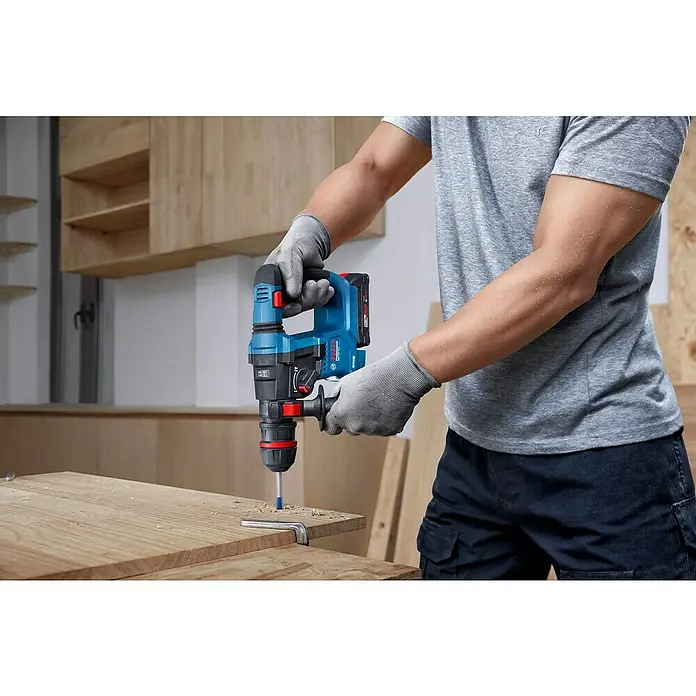 Bosch Professional AMPShare 18V Akku-Bohrhammer GBH 18V-18X - 18 V, Ohne Akku, 1,5 J - Ein Arbeiter bohrt mit einem Bosch-Bohrhammer ein Loch in ein Holzbrett. Akkubohrer für professionelle Handwerker.