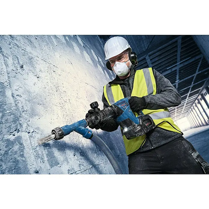 Bosch Professional AMPShare 18V Akku-Schlaghammer GSH 18V-5 - 18 V, Ohne Akku, 8,5 J - Ein Bauarbeiter benutzt einen Bosch Abbruchhammer mit Staubabsaugung an einer Betonwand, um Staub zu reduzieren und die Arbeitssicherheit zu erhöhen.