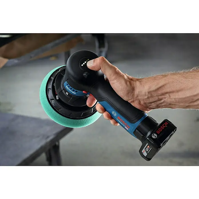 Bosch Professional Akku-Poliermaschine GPX 12V-125 - 12 V, Ohne Akku, Leerlaufdrehzahl: 1.400 U/min - 7.000 U/min - Nahaufnahme eines Bosch Akku-Poliermaschine mit grünem Polieraufsatz, die von einer Hand gehalten wird.
