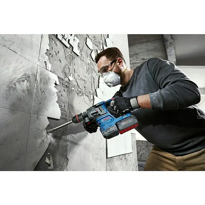 Bosch Professional AMPShare 18V Akku-Bohrhammer GBH 18V-22X - 18 V, Ohne Akku, 2 J - Ein Mann entfernt Fliesen mit einem Bosch Bohrhammer. Der Bohrhammer ist blau und hat einen roten Akku, er ist robust und leistungsstark.