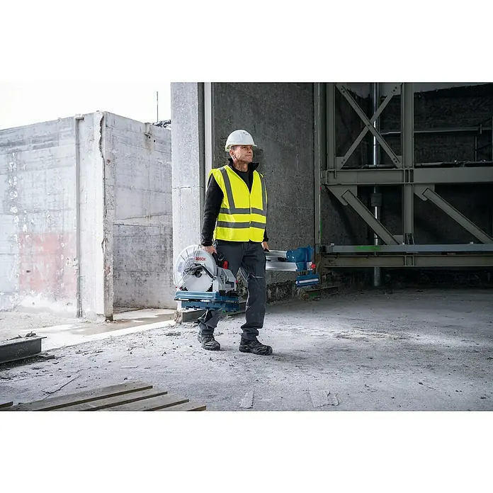 Bosch Professional AMPShare 18V Akku-Metalltrennsäge GCD 18V-355 - 18 V, Ohne Akku, 1.300 U/min - Mann mit Bosch Kapp- und Gehrungssäge im Baugebiet. Die Säge ist silbern mit blauen Akzenten und präzise für professionelle Schnitte.