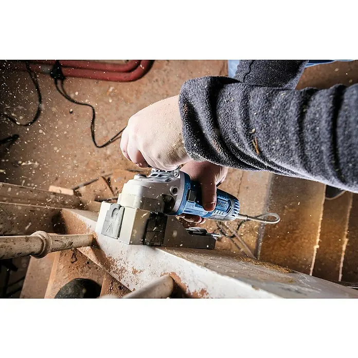 Scheppach Lijadora excéntrica eléctrica LFR720 - 720 W - Un artesano utiliza una fresadora de ranuras Scheppach para serrar una pieza de madera. Las virutas vuelan alrededor.