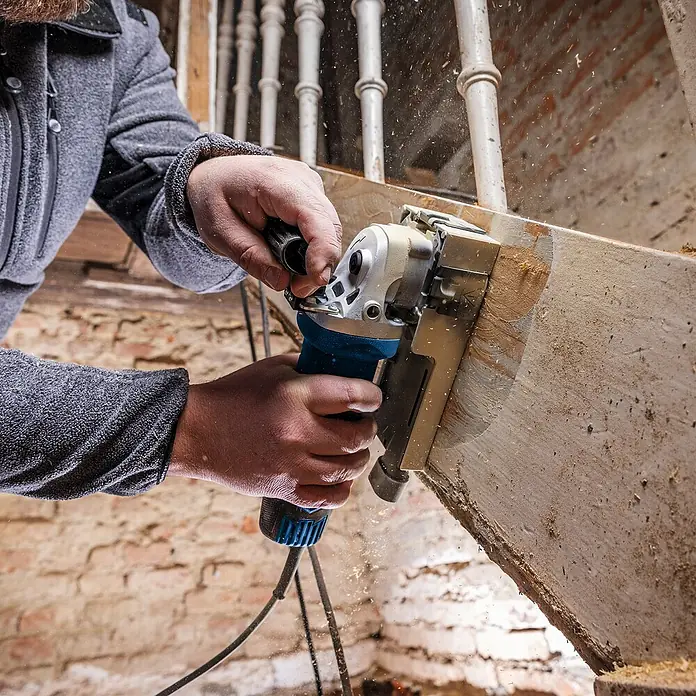 Scheppach Elektro-Exzenterschleifer LFR720 - 720 W - Nahaufnahme eines Mannes, der mit einer blauen und silbernen Elektromühle ein Stück Holz bearbeitet.