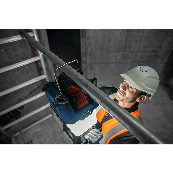 Bosch Professional AMPShare 18V Akku-Bauleuchte - 18 V, Anzahl Akkus: Ohne Akku, 7.500 lm - Ein Bauarbeiter befestigt eine akkubetriebene Baustellenleuchte mit Haken an einer Stange in einem Rohbau, um den Arbeitsbereich optimal auszuleuchten.