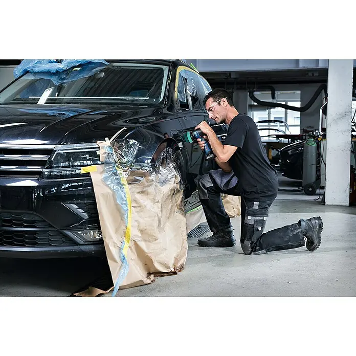 Bosch Professional Akku-Poliermaschine GPX 12V-77 - 12 V, Ohne Akku, Leerlaufdrehzahl: 1.400 U/min - 7.000 U/min - Ein Mechaniker, der an einem schwarzen Auto in einer Werkstatt arbeitet und dabei einen Bohrer benutzt.
