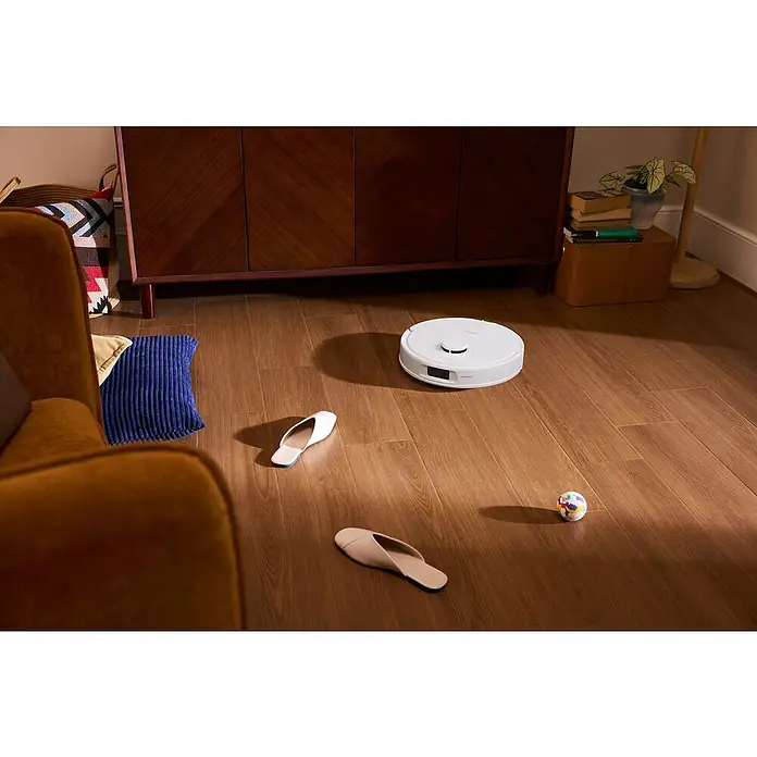 Roborock Saugwischroboter QR 598 White - Saugkraft: 8.000 Pa, Akkulaufzeit: 180 min, Fassungsvermögen Roboter: 330 ml, Weiß - Ein weißer Saugroboter navigiert auf einem Holzboden zwischen Hausschuhen und einem Ball. Der Saugroboter ist das Hauptprodukt im Bild.