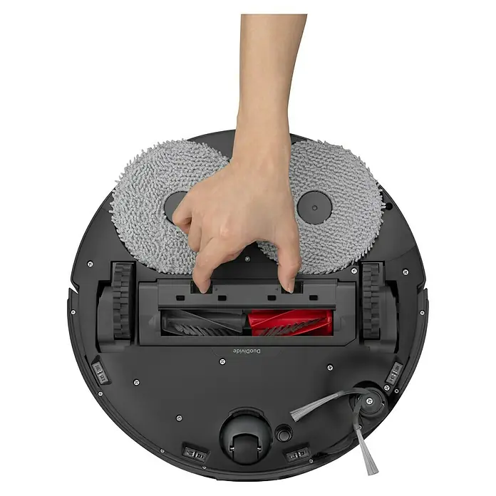 Roborock Saugwischroboter Qrevo Edge 5V1 Black - Saugkraft: 18.500 Pa, Akkulaufzeit: 180 min, Fassungsvermögen Roboter: 325 ml, Schwarz - Nahaufnahme eines Saugroboters, der von einer Hand bedient wird. Der Roboter verfügt über rotierende Wischmopps und eine Bürstenwalze.
