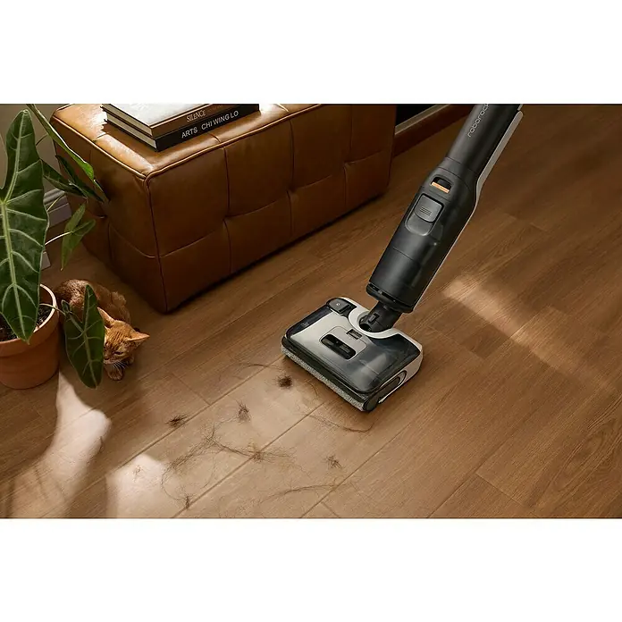 Roborock Akku-Nass-Trockensauger F25 - Saugkraft: 20.000 Pa, Akkulaufzeit: 60 min, Wassertankvolumen: 0,87 l - Hier ist ein Roborock Staubsauger in Aktion, der Haare auf einem Holzboden aufsaugt, neben einer Katze und einem dekorativen Hocker.