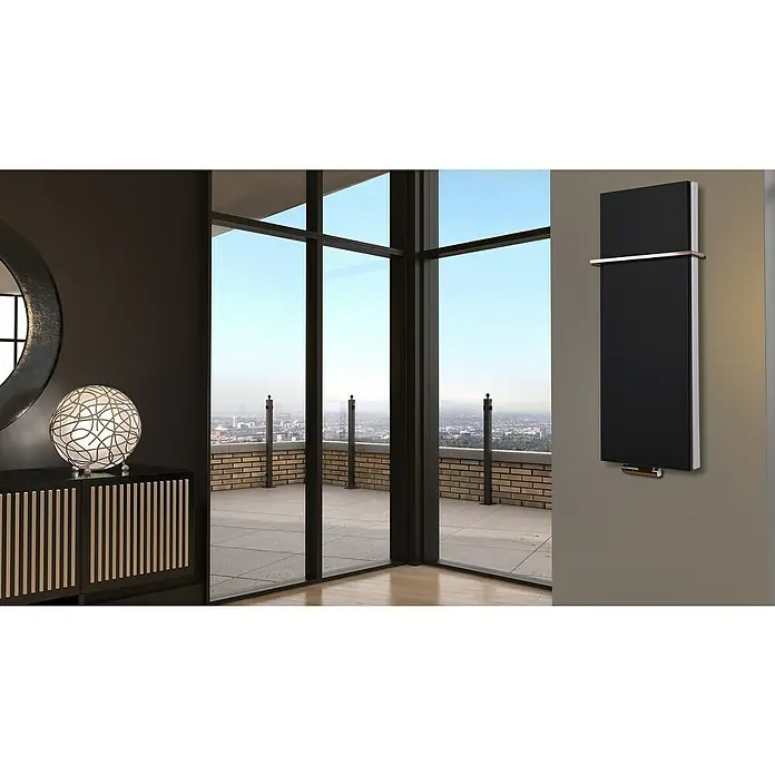Badheizkörper Manhattan - B x H: 470 x 1.200 mm, Schwarz, Mit Halter 15mm, Nennleistung: 1.458 W - Ein modernes, schwarzes Heizkörperelement mit Chromakzenten hängt an einer grauen Wand in einem stilvollen Raum.
