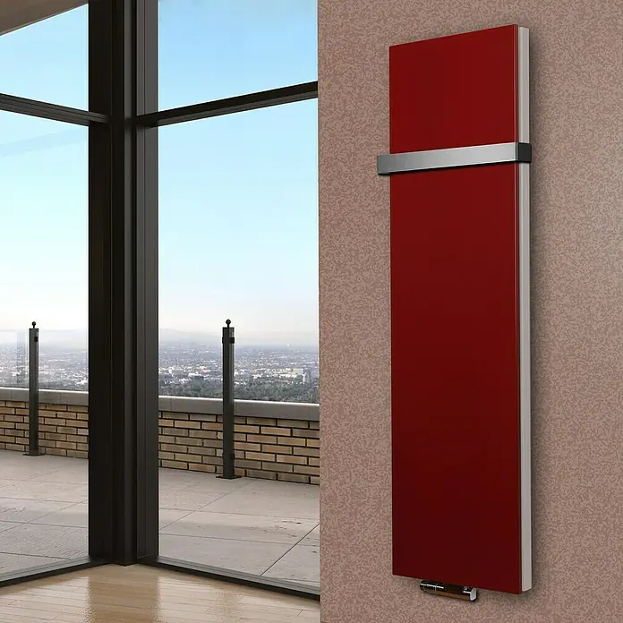 Badheizkörper Manhattan - B x H: 470 x 1.800 mm, Rot, 1 x Halter 50mm, Nennleistung: 1.964 W - Roter Design-Heizkörper hängt an einer Wand mit gemusterter Tapete, ein Fenster mit Ausblick auf die Stadt befindet sich daneben.