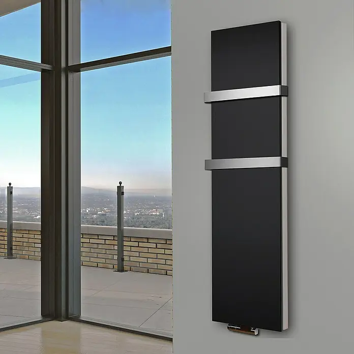 Badheizkörper Manhattan - B x H: 470 x 1.800 mm, Schwarz, 2 x Halter 50mm, Nennleistung: 1.964 W - Stilvoller schwarzer Heizkörper mit silbernen Akzenten vor einem Fenster mit Blick auf eine Stadt.