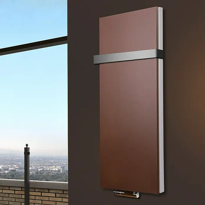 Badheizkörper Manhattan - B x H: 470 x 1.200 mm, Braun, Mit Halter 50mm, Nennleistung: 1.458 W - Braun lackierter Heizkörper mit silberner Halterung, der an einer braunen Wand hängt. Im Hintergrund eine schöne Aussicht.