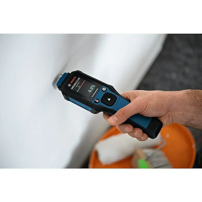 Bosch Feuchtigkeitsmessgerät GMP 2-15 - Messgenauigkeit: Umgebungstemperatur typisch: +/- 1 °C, Mit Batterien - Nahaufnahme eines Bosch-Feuchtigkeitsmessgeräts, das in einer Hand gehalten wird und eine Messung an einer weißen Oberfläche durchführt.