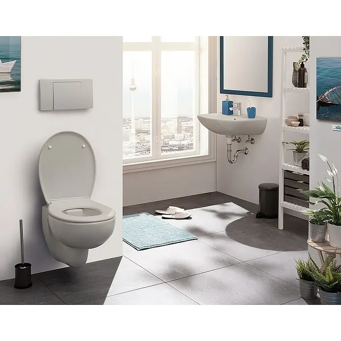 Calmwaters WC-Sitz Original - Duroplast, Grau, Mit Absenkautomatik - Badezimmer-Szene mit einer wandmontierten Toilette, einem Waschbecken, einem Spiegel und einem Regal, die eine moderne und funktionale Raumlösung zeigen.