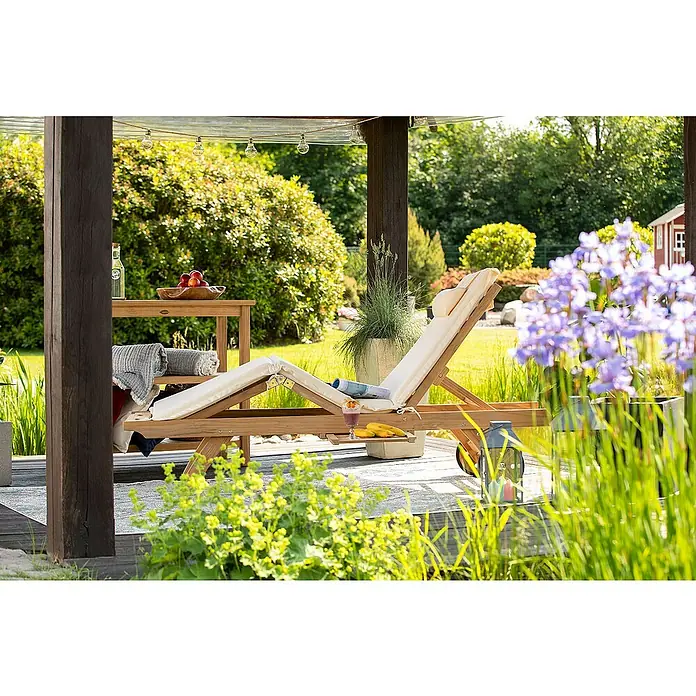 Kai Wiechmann Gartenliege - Naturbelassen, Holz, Rollbar - Gartenmöbel-Szene mit einer hölzernen Sonnenliege unter einer Pergola, die zum Entspannen im Freien einlädt, umgeben von üppigem Grün.